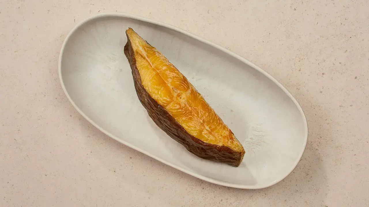 Ein goldbraunes Stück schwarzer Heilbutt liegt auf einer ovalen Schale. Dieser Fisch ist nicht nur lecker, sondern auch gesund.