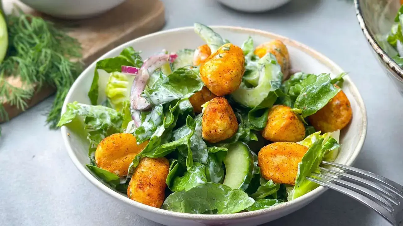 Knuspriger Gnocchi Salat mit Gurke, Salat und Zwiebeln, serviert in einer Schüssel mit einer Gabel.