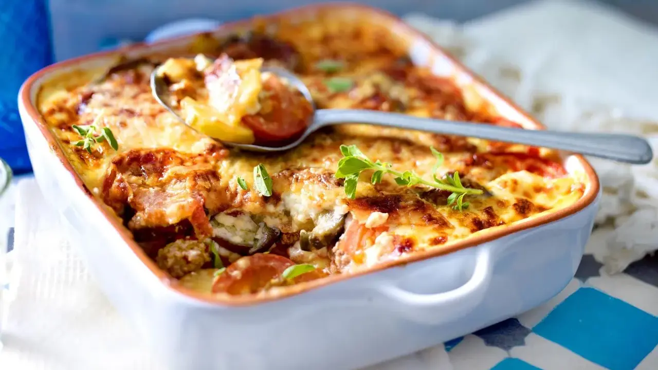 Herzhaftes Moussaka Rezept Original Griechisch, goldbraun überbacken mit Käse und frischen Kräutern, serviert in einer Auflaufform.