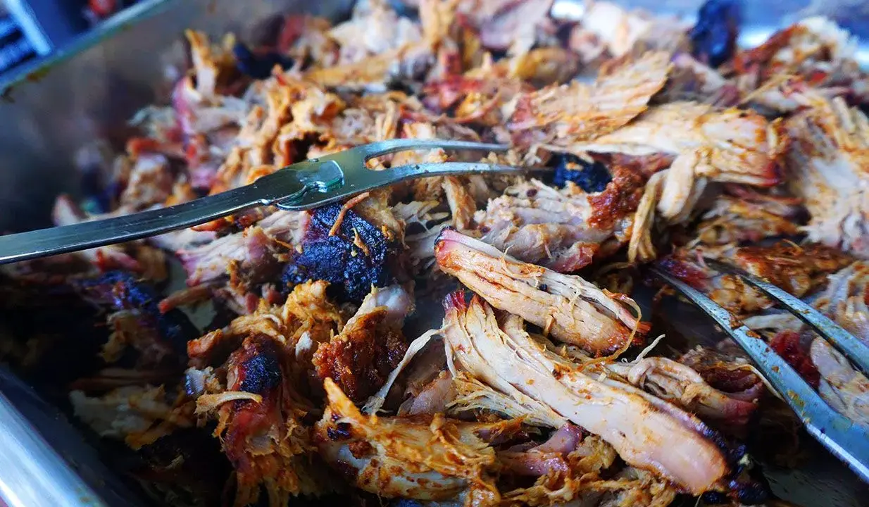 Saftiges, zartes Pulled Pork im Texas-Stil, bereit zum Servieren. Ein Gabel hebt die köstlichen Fleischfasern an.