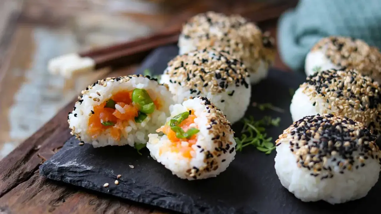 Leckere Onigiri selber machen: Reisbällchen mit Lachsfüllung, umhüllt von schwarzem und weißem Sesam.