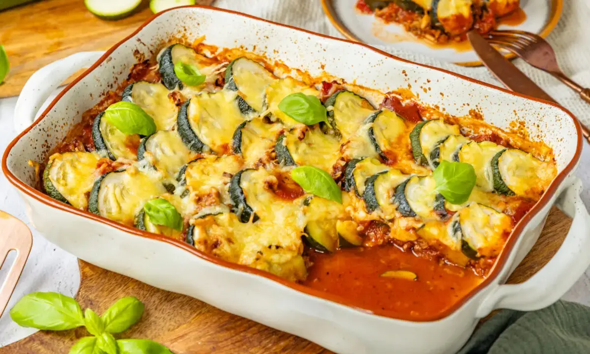 Herzhafter Zucchini Hackfleisch Auflauf mit geschmolzenem Käse und frischem Basilikum, bereit zum Servieren.