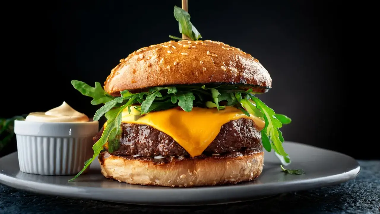 Saftiger Wagyu Burger mit geschmolzenem Käse, Rucola und einer Beilage Sauce. Ein perfektes Wagyu Burger Rezept für Genießer.