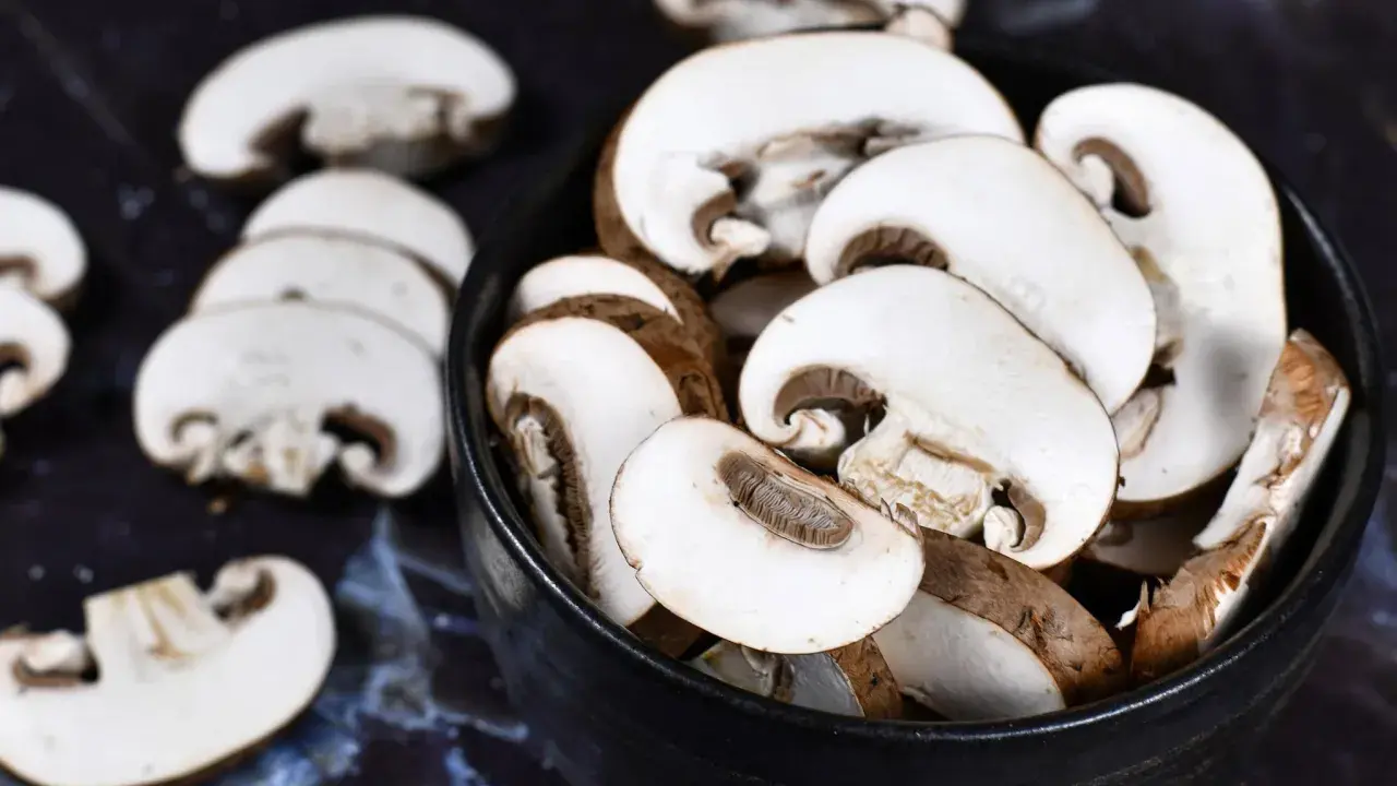 Ein schwarzer Teller mit geschnittenen braunen Champignons. Sie warten darauf, geputzt und zubereitet zu werden.