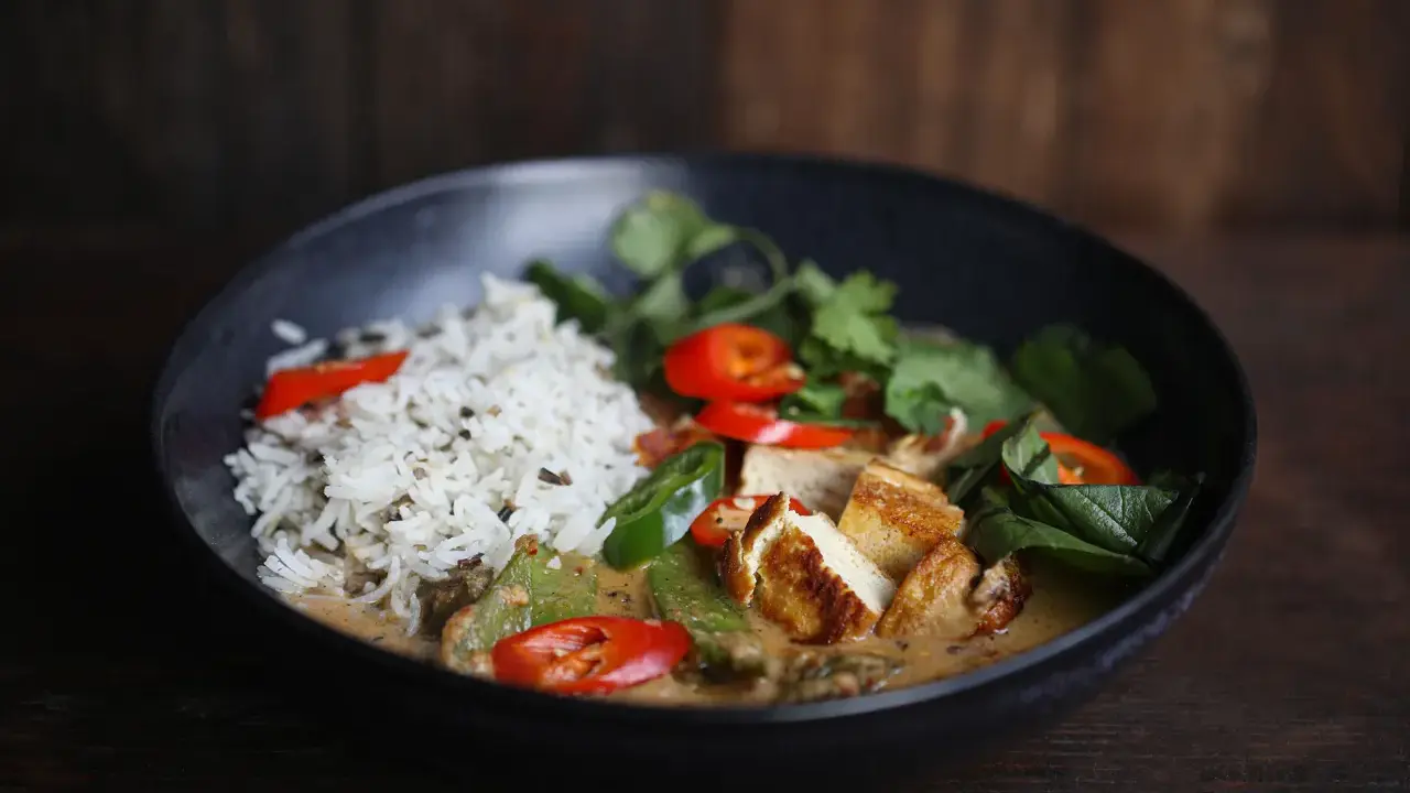 Ein köstliches Thai Curry Rezept mit Reis, gebratenem Tofu, Chili und frischen Kräutern in einer cremigen Sauce.