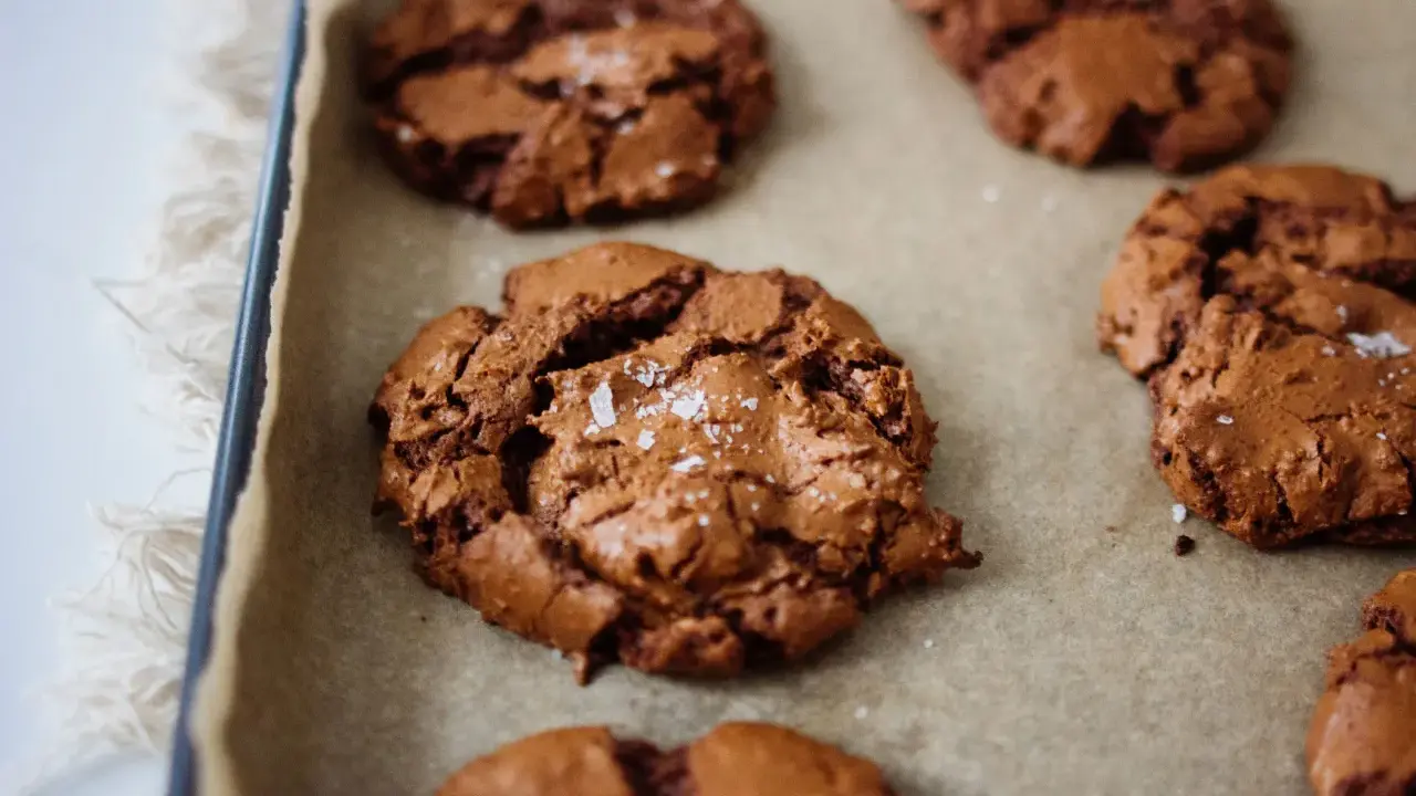 Frisch gebackene, schoko cookies rezept einfach, mit Meersalz bestreut, auf Backpapier.