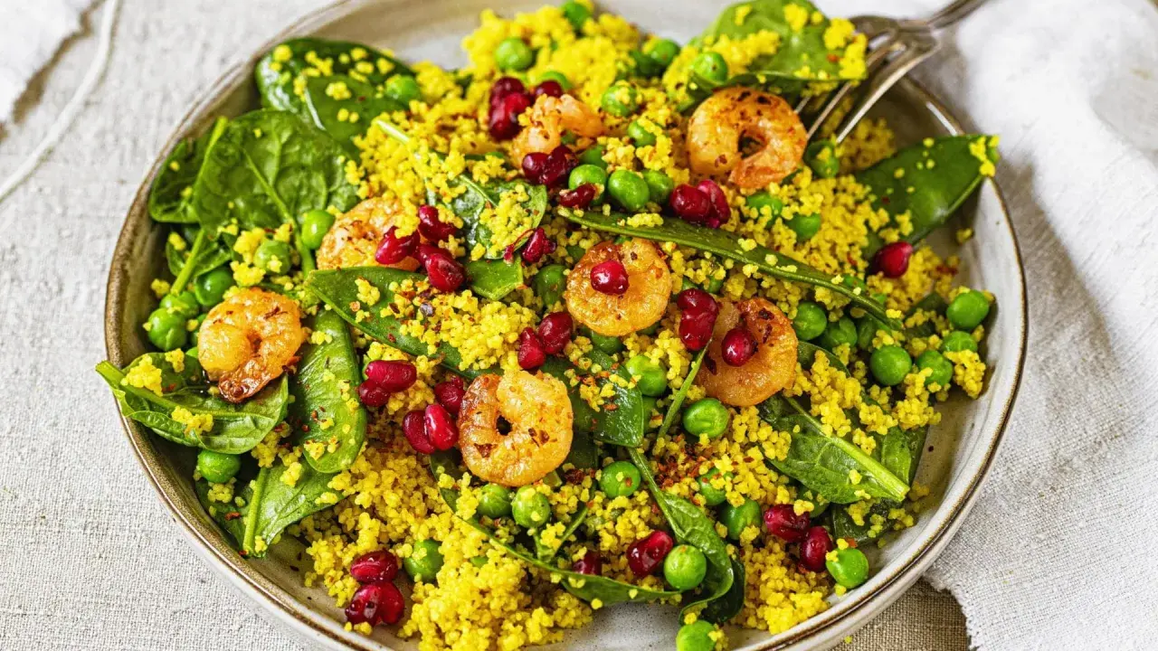 Bunter Couscous-Salat mit Garnelen, Erbsen, Spinat und Granatapfelkernen. Ein leichter und gesunder Genuss.