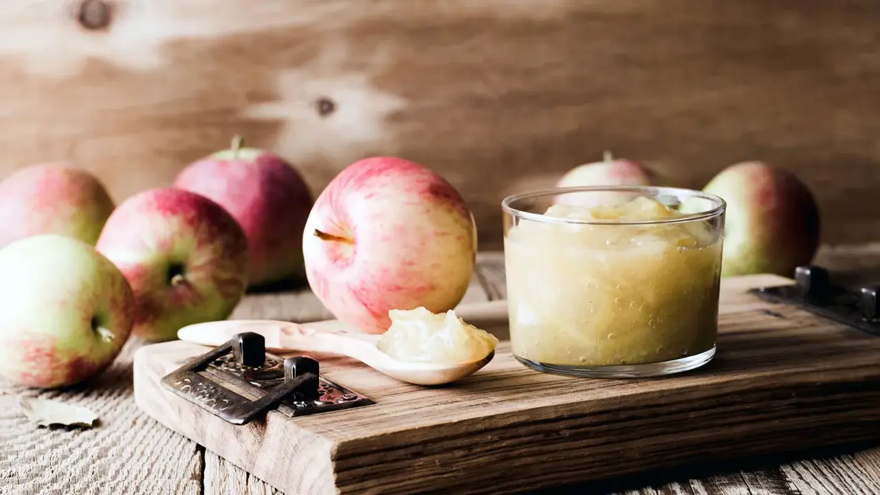 Frische Äpfel und selbstgemachtes Apfelmus im Glas, bereit zum Apfelmus im Backofen einkochen.