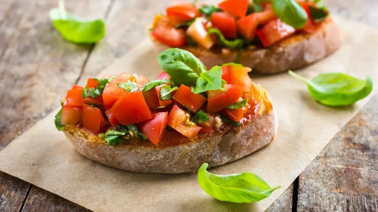 Zwei Bruschetta mit Tomaten und Basilikum, ein authentisches italienisches Rezept, auf rustikalem Holz.
