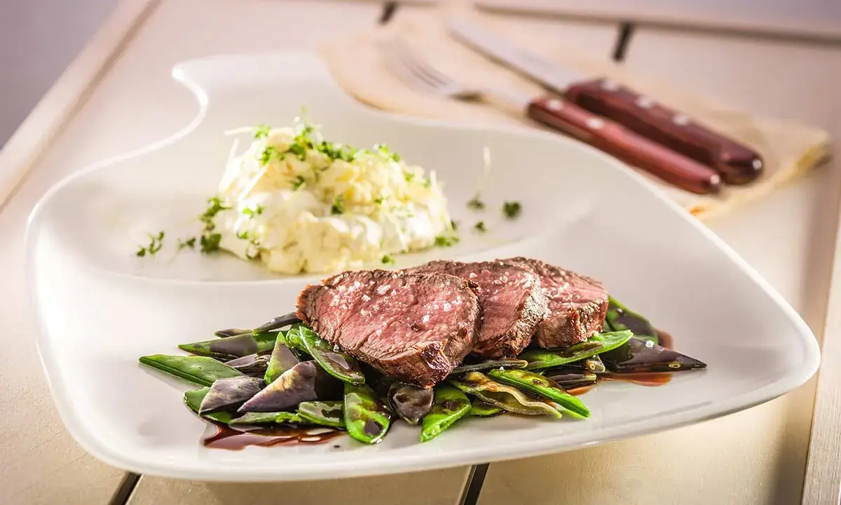 Sternekoch-Qualität: Zartes Kalbsfilet mit knackigen Zuckerschoten und cremigem Kartoffelsalat. Ein Genuss für jeden Gaumen.