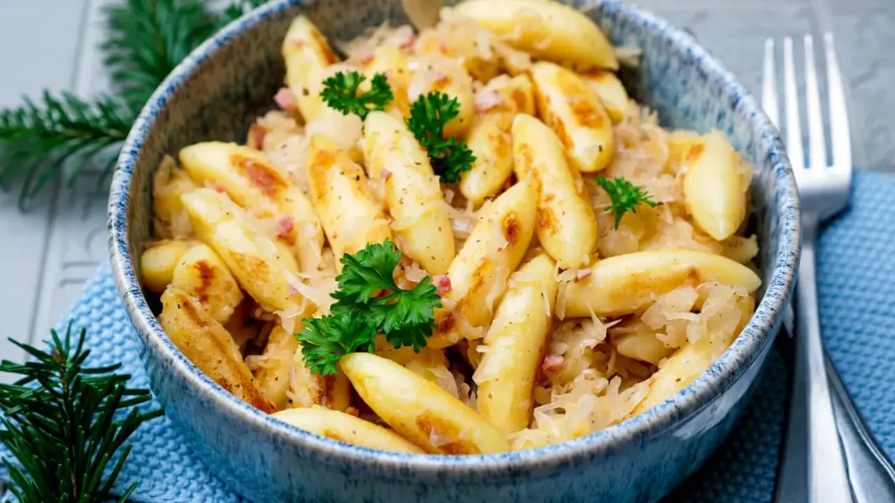 Schupfnudeln mit Sauerkraut, garniert mit Petersilie, in einer blauen Schüssel. Ein Klassiker der deutschen Küche.