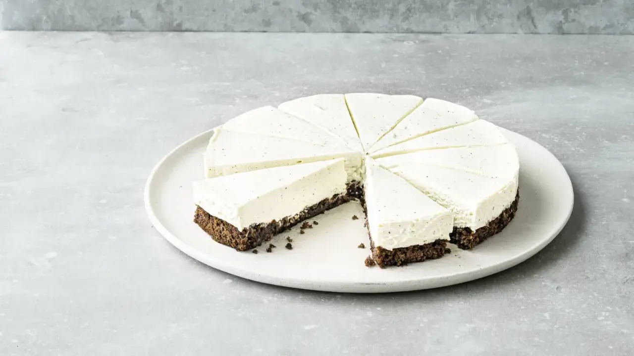 Cremiger Kuchen ohne Mehl, in Tortenstücke geschnitten, mit dunklem Boden und heller Füllung, garniert mit Vanillepunkten.