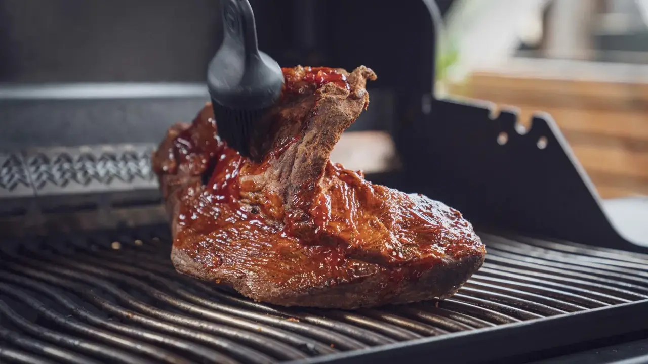 Ein saftiges Brisket, sous vide gegart, wird mit einer BBQ-Sauce auf dem Grill glasiert.