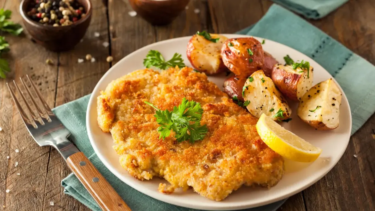 Goldbraunes Schnitzel, perfekt paniert, mit Rosmarinkartoffeln und Zitrone. Die richtige schnitzel panieren reihenfolge macht's!