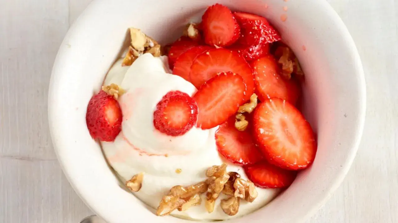Cremiger Skyr mit frischen Erdbeeren und knackigen Walnüssen in einer weißen Schale, ein Genuss für Augen und Gaumen.