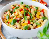 Bester Pasta Salat ohne Mayonnaise: Spiralnudeln mit Schinken, Erbsen, Paprika und Basilikum in einer weißen Schüssel.