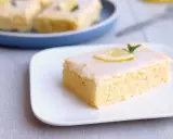 Ein Stück von Omas Zitronenkuchen vom Blech, mit Zuckerguss und Zitronenscheibe garniert.