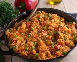 Djuvec Reis mit Erbsen und Paprika in einer Gusseisenpfanne, bereit zum Servieren.