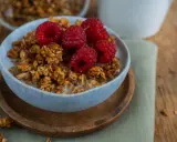 Schüssel mit selbstgemachtem Granola, Milch und frischen Himbeeren. Ein gesunder Start in den Tag!