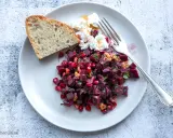 Ein bunter rote beete salat mit Granatapfelkernen, Nüssen und Ziegenkäse, serviert mit Brot.