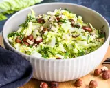 Frischer Chinakohlsalat mit gehackten Haselnüssen und Petersilie, garniert mit ganzen Nüssen.