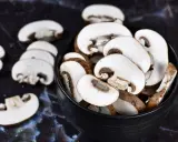 Ein schwarzer Teller mit geschnittenen braunen Champignons. Sie warten darauf, geputzt und zubereitet zu werden.