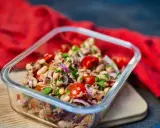 Frischer Thunfischsalat mit weißen Bohnen, Tomaten und roten Zwiebeln in einer Glasbox, bereit zum Mitnehmen.