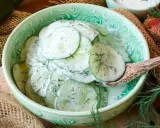 Frischer gurkensalat mit saurer sahne und dill, serviert in einer grünen schüssel.