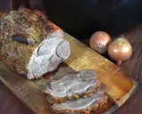 Saftiger Rinderbraten aus dem Dutch Oven, auf einem Holzbrett mit Zwiebeln.