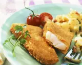 Knuspriger Backfisch mit cremigem Kartoffelsalat und frischer Petersilie, garniert mit Kirschtomaten.