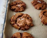 Frisch gebackene, schoko cookies rezept einfach, mit Meersalz bestreut, auf Backpapier.