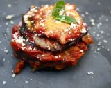 Melanzane alla Parmigiana: geschichtete Aubergine mit Tomatensauce, Käse und Basilikum, bestreut mit Parmesan.