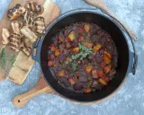 Herzhaftes Rindfleischgulasch im Dutch Oven, mit Kartoffeln, Karotten und Erbsen. Dazu geröstetes Brot. Perfekt für Dutch Oven Rezepte Rind.
