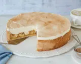 Saftige Apfel-Schmand-Torte mit Zimt bestäubt, ein Stück herausgeschnitten, daneben eine Tasse Cappuccino.
