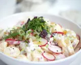 Ein cremiger Kartoffel Radieschen Salat, garniert mit frischen Kräutern und Frühlingszwiebeln.