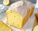 Saftiger Zitronenkuchen mit Zuckerguss, der aussieht wie der beste zitronenkuchen der welt. Ein Stück ist bereits angeschnitten.
