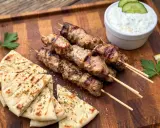 Gegrillte Souvlaki-Spieße mit Schweinefleisch, dazu Pitabrot, Tzatziki und Zitrone.