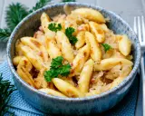 Schupfnudeln mit Sauerkraut, garniert mit Petersilie, in einer blauen Schüssel. Ein Klassiker der deutschen Küche.