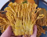 Knusprige Enoki Pilze, perfekt für ein einfaches enoki pilze rezept. Goldbraun frittiert und auf einem blauen Teller serviert.