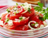 Frischer Tomatensalat mit Feta, Zwiebeln und Petersilie, garniert mit grobem Salz und Pfeffer. Ein leichter Genuss!