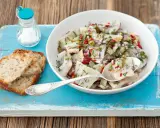 Frischer Matjessalat mit Gurke und Zwiebeln, garniert mit Dill, serviert mit Brot.