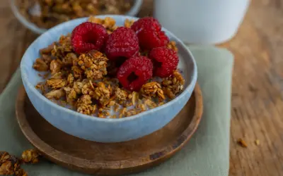 Schüssel mit selbstgemachtem Granola, Milch und frischen Himbeeren. Ein gesunder Start in den Tag!