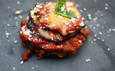 Melanzane alla Parmigiana: geschichtete Aubergine mit Tomatensauce, Käse und Basilikum, bestreut mit Parmesan.