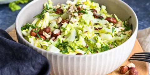 Frischer Chinakohlsalat mit gehackten Haselnüssen und Petersilie, garniert mit ganzen Nüssen.