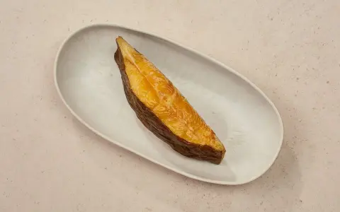 Ein goldbraunes Stück schwarzer Heilbutt liegt auf einer ovalen Schale. Dieser Fisch ist nicht nur lecker, sondern auch gesund.