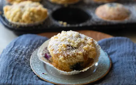 Saftige Blaubeermuffins mit Joghurt und Streuseln, bestäubt mit Puderzucker.