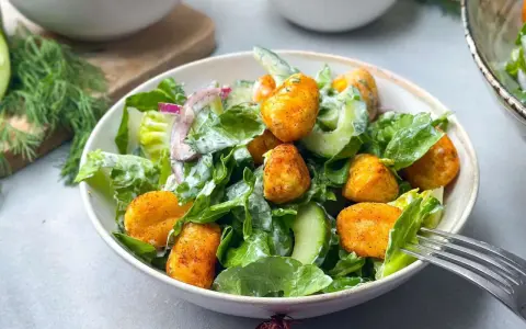 Knuspriger Gnocchi Salat mit Gurke, Salat und Zwiebeln, serviert in einer Schüssel mit einer Gabel.