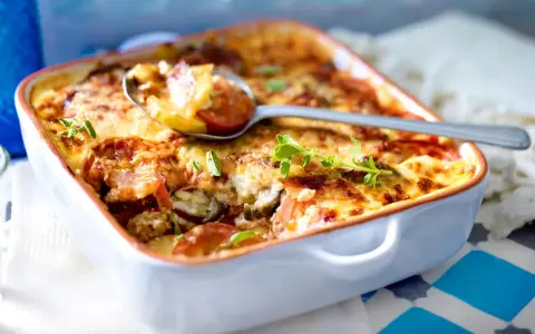 Herzhaftes Moussaka Rezept Original Griechisch, goldbraun überbacken mit Käse und frischen Kräutern, serviert in einer Auflaufform.