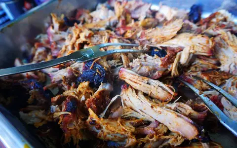 Saftiges, zartes Pulled Pork im Texas-Stil, bereit zum Servieren. Ein Gabel hebt die köstlichen Fleischfasern an.