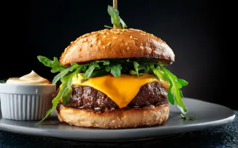 Saftiger Wagyu Burger mit geschmolzenem Käse, Rucola und einer Beilage Sauce. Ein perfektes Wagyu Burger Rezept für Genießer.